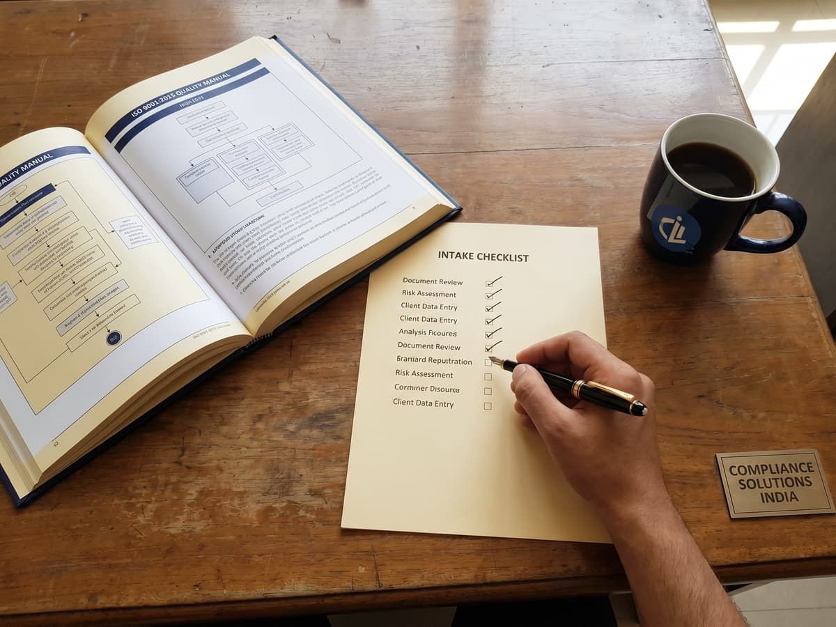 An ISO 9001:2015 quality manual and intake checklist on a desk